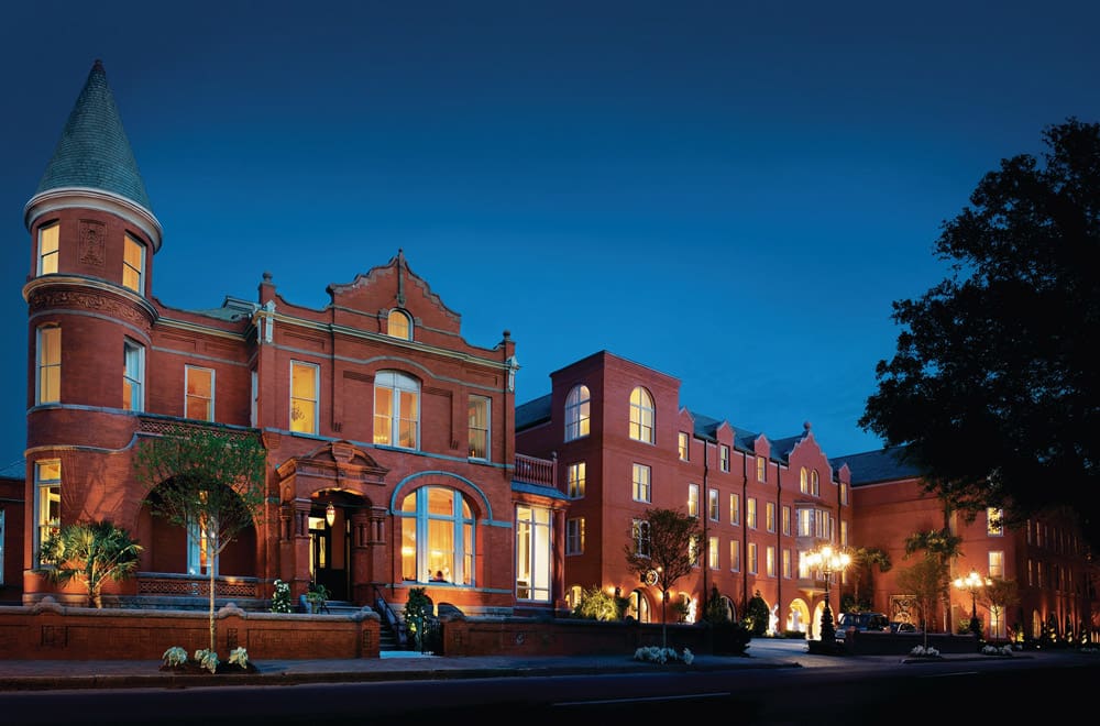 The lit-up entrance to the Mansion on Forsyth Park, Autograph Collection at night.