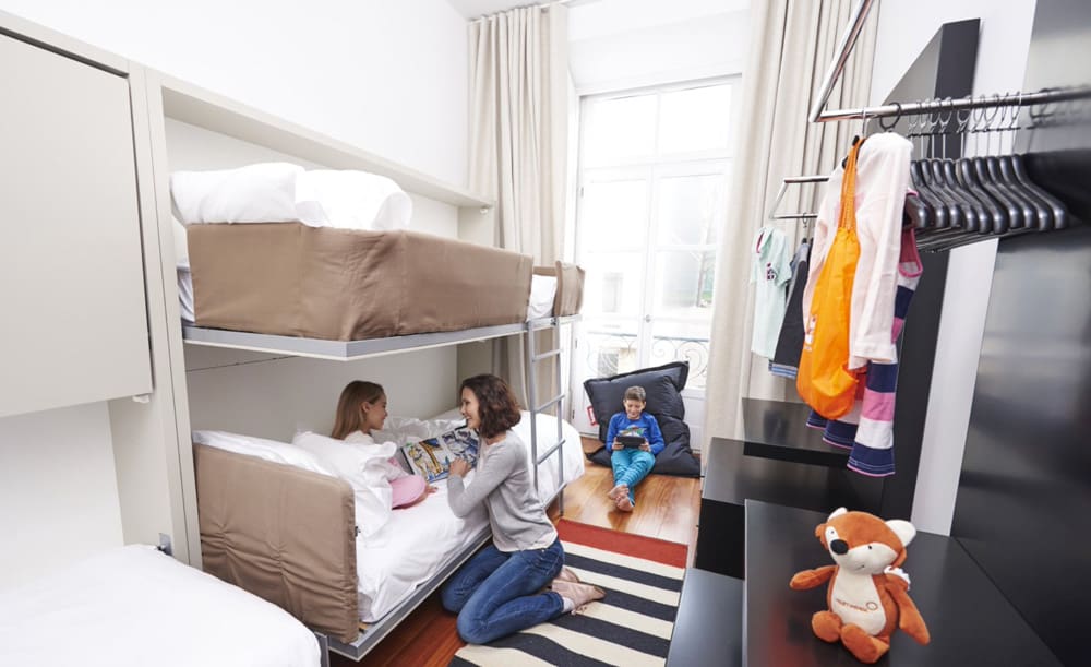 A mom and daughter sit together in a bunk bed room at Martinhal Lisbon Chiado Family Suites, one of the best Lisbon hotels for families.