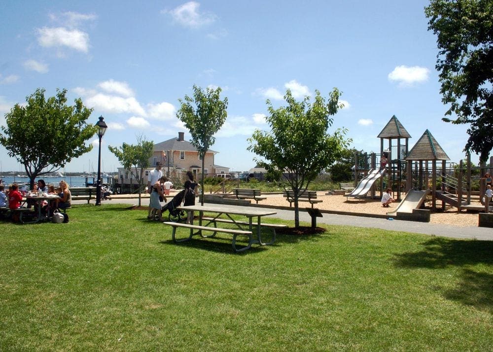 Families play at the playground on-sites at Children's Beach in Nantucket on a sunny day, a great spot to explore on at family vacation to Nantucket.