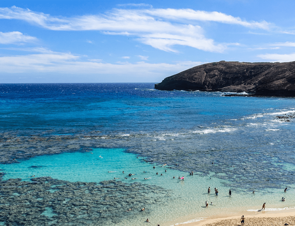 Several people wade in shallow water at Hanauma Bay.