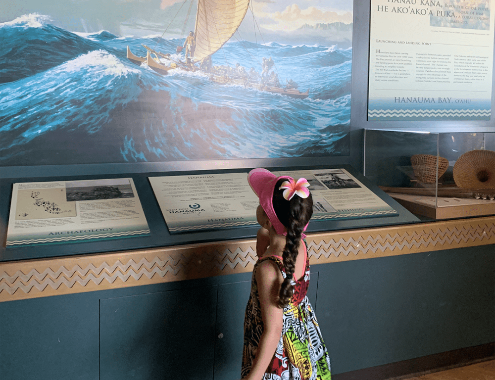 A young girl reads a museum plaque at the Nature Preserve and Marine Life Conservation Area, one of the Hanauma Bay Nature Preserve with kids.
