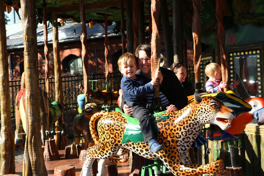 A mom and her young son enjoy a ride on a carousel in Philadelphia, one of the best weekend getaways near DC for families.