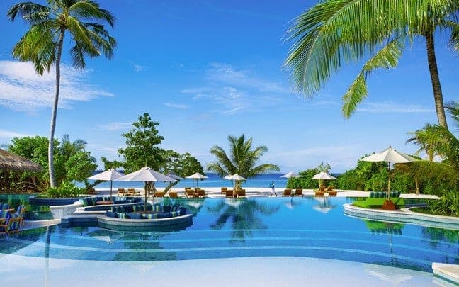 Several people enjyo time in the pool at Six Senses Laamu, one of the best family hotels in the Maldives.