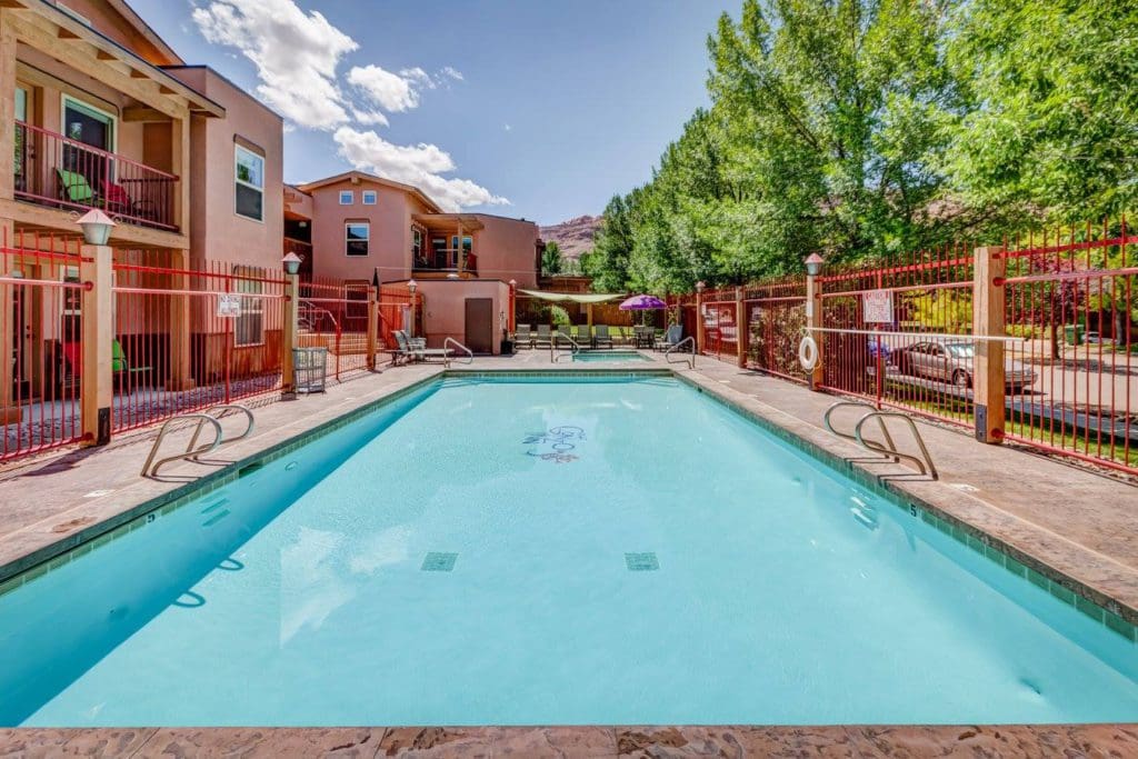 The outdoor pool at the The Gonzo Inn, with resort buildings on one side and trees on the other.