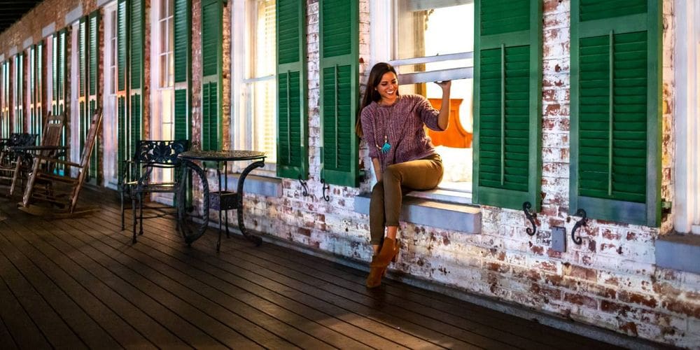 A woman sits in a historic window on the terrace of the The Marshall House, Historic Inns of Savannah.