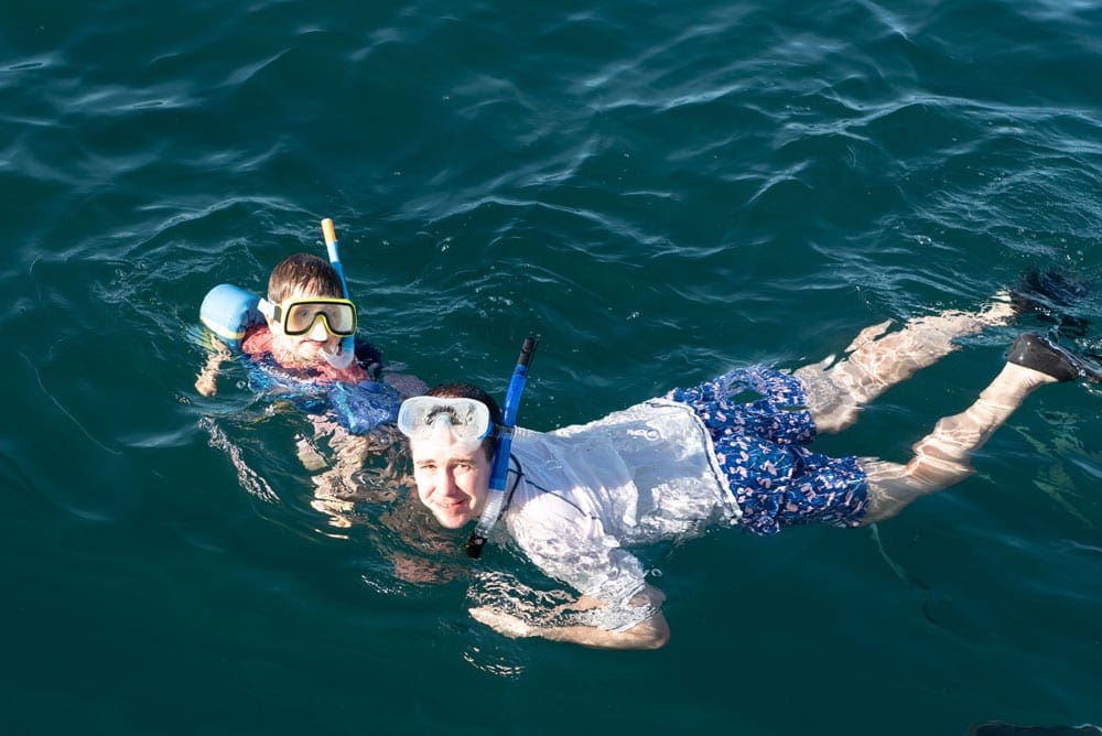 A young boy and his dad snorkel in the ocean, one of the best things to do in Kauai with kids.