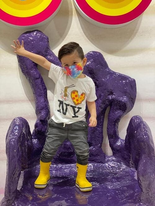 A young boy stands on a chair made of fake slime at the Sloomoo Institute.