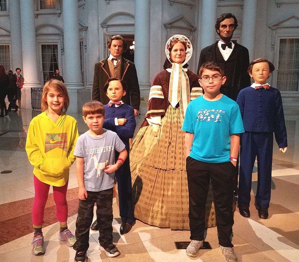 Three kids stand amongst five wax statues of Abriham Lincoln, his wife and three others at the Springfield Lincoln Museum.