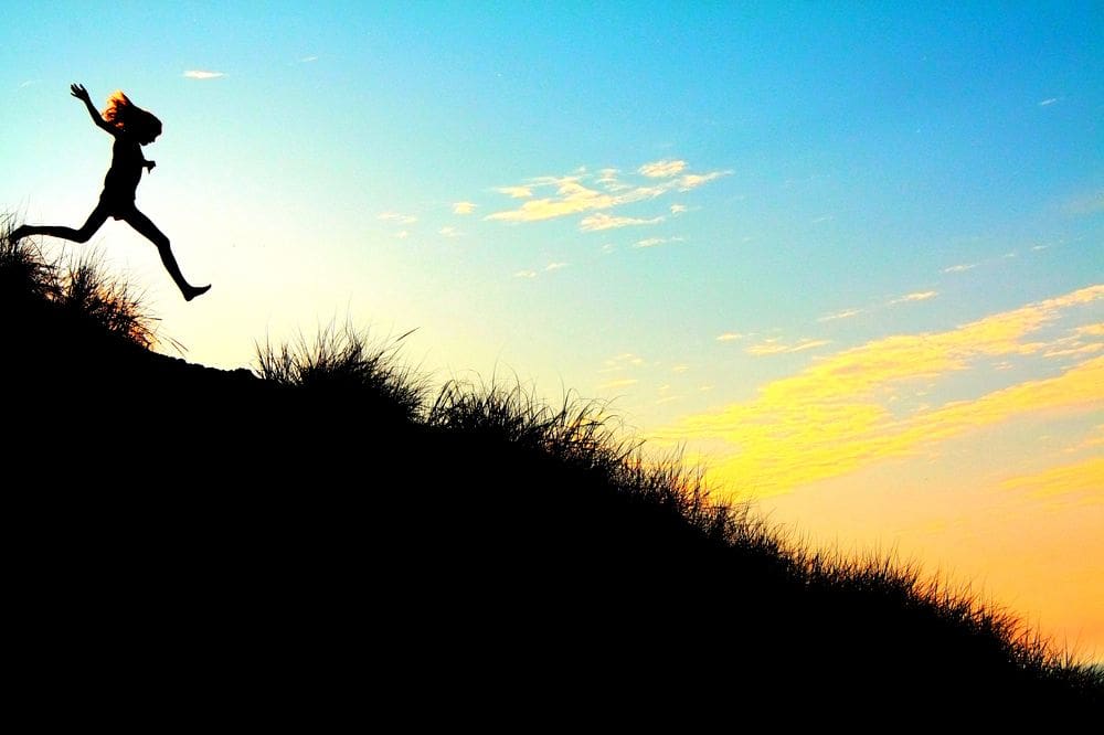 A young woman runs along the dunes on a sunny evening at Indiana Dunes National Park, one of the best weekend getaways near Chicago for families