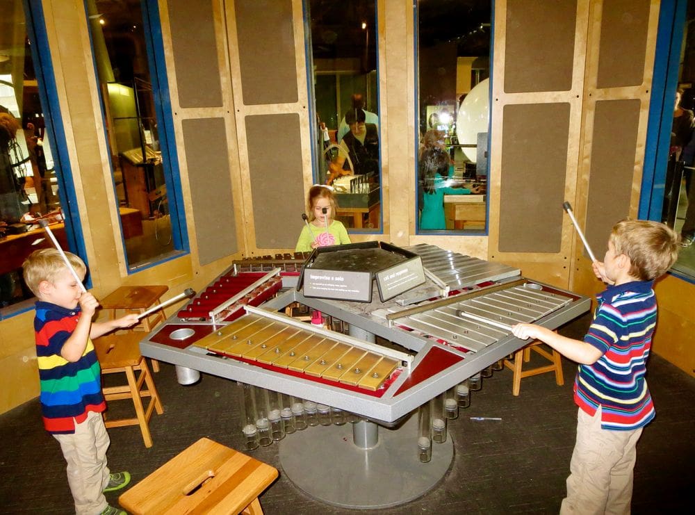 Three kids play on a large xylophone while exploring the Exploratorium, one of the best things to do in San Francisco with kids.