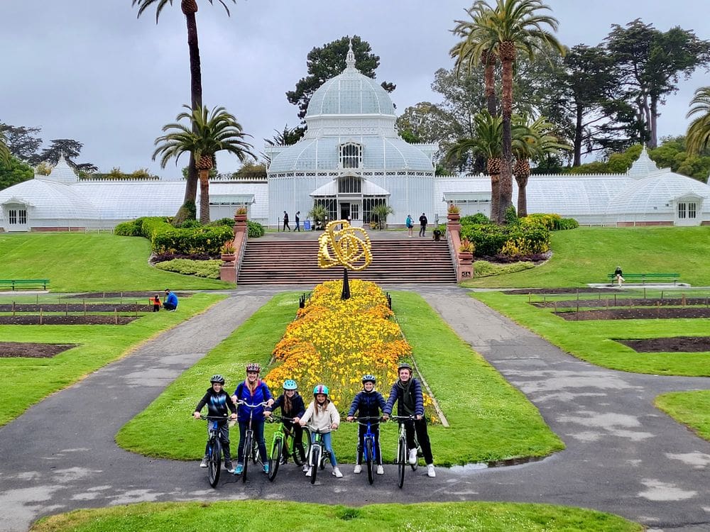 A family of six sits on their bikes while on a tour of Golden Gate Park, one of the best places to visit in California with kids!