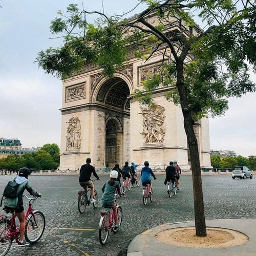 A large bike tour races by the Arc de Triomphe.