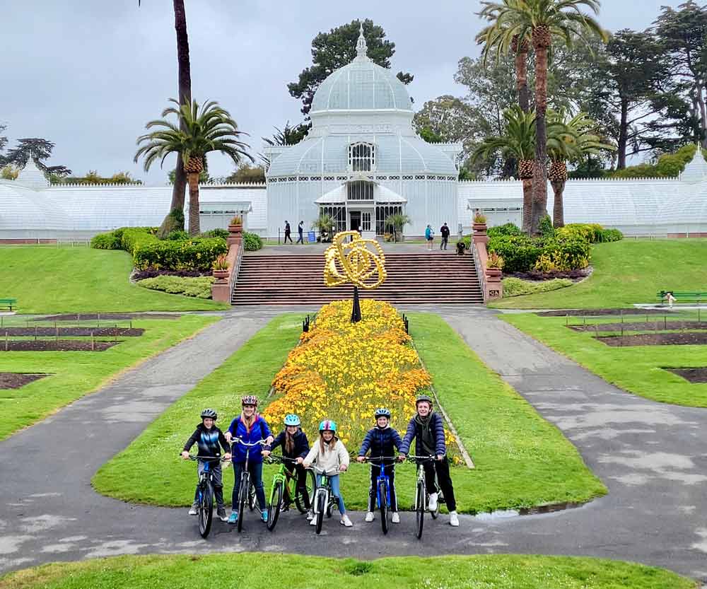 A family of six sits on their bikes while on a tour of Golden Gate Park.