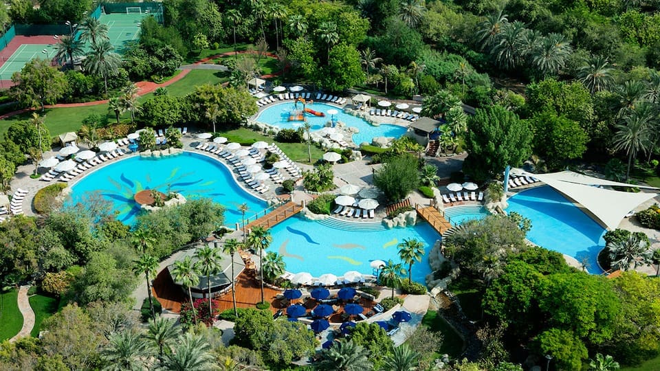 An aerial view of the large hotel pool and pool deck at the Grand Hyatt Hotel and Residences Dubai, one of the best family hotels in Dubai.