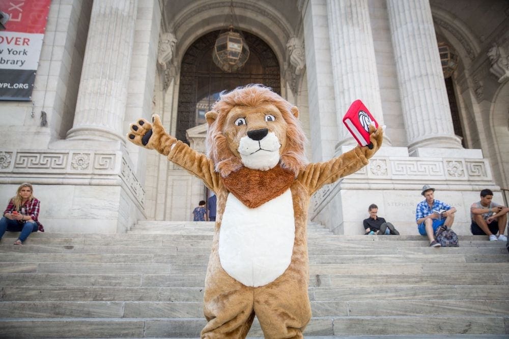 A large lion mascot holds a book outside the NYPL The New York Public Library.