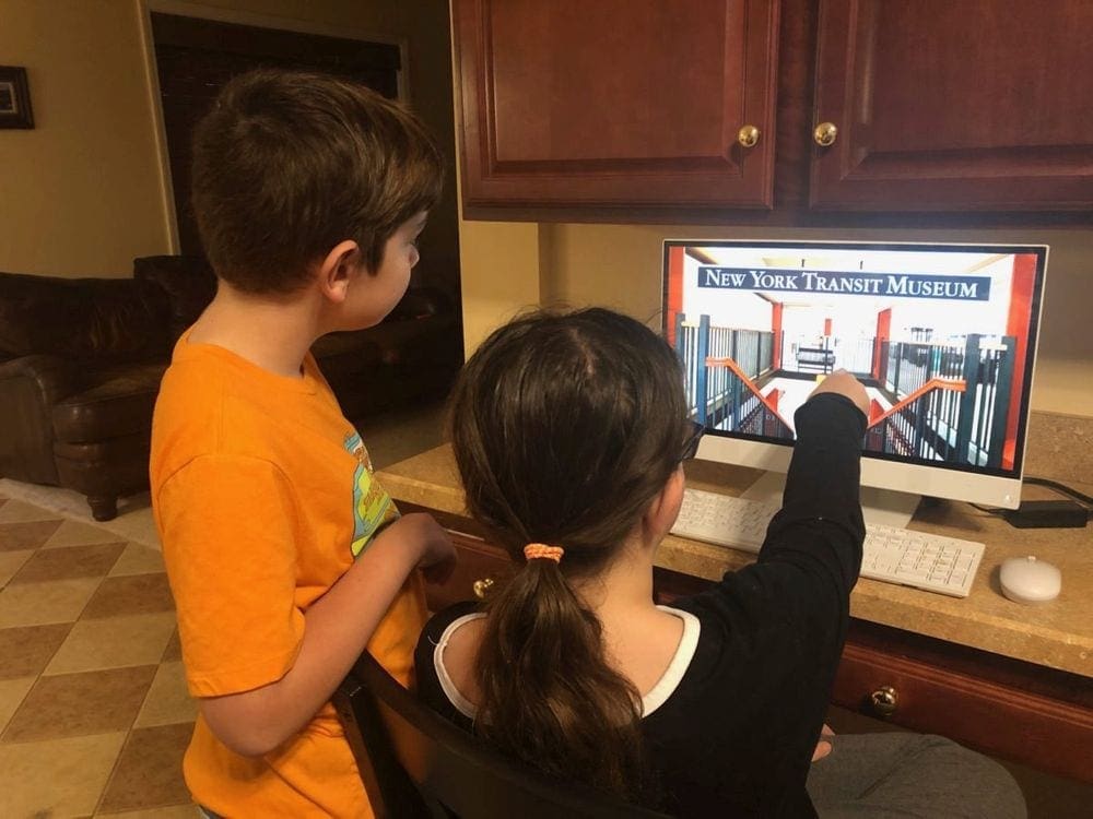 Two kids look at an interactive screen at the New York Transit Museum.