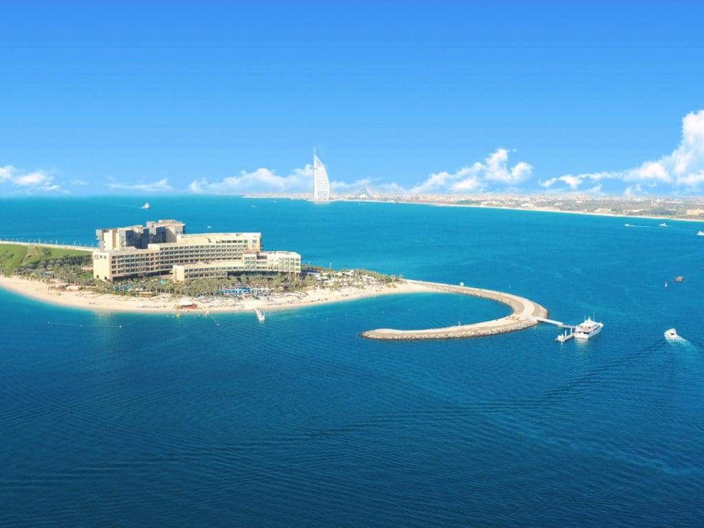 An aerial view of the impressive Rixos The Palm Hotel and Suites Dubai, set at the end of a peninsual with expansive beach access.