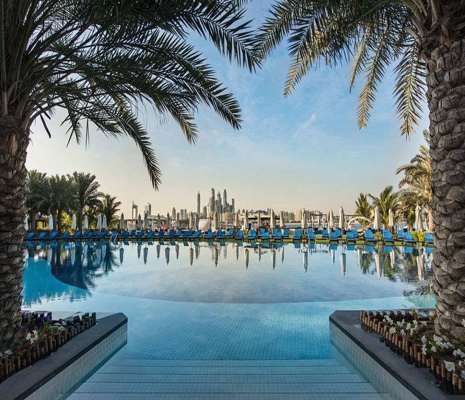 A close up of one of the pools at Rixos The Palm Hotel and Suites, one of the best family hotels in Dubai, with a distant view of the Dubai skyline.