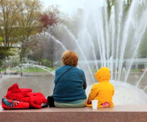 Grandma and kid sitting facing the fountain in Seattle, Washington.