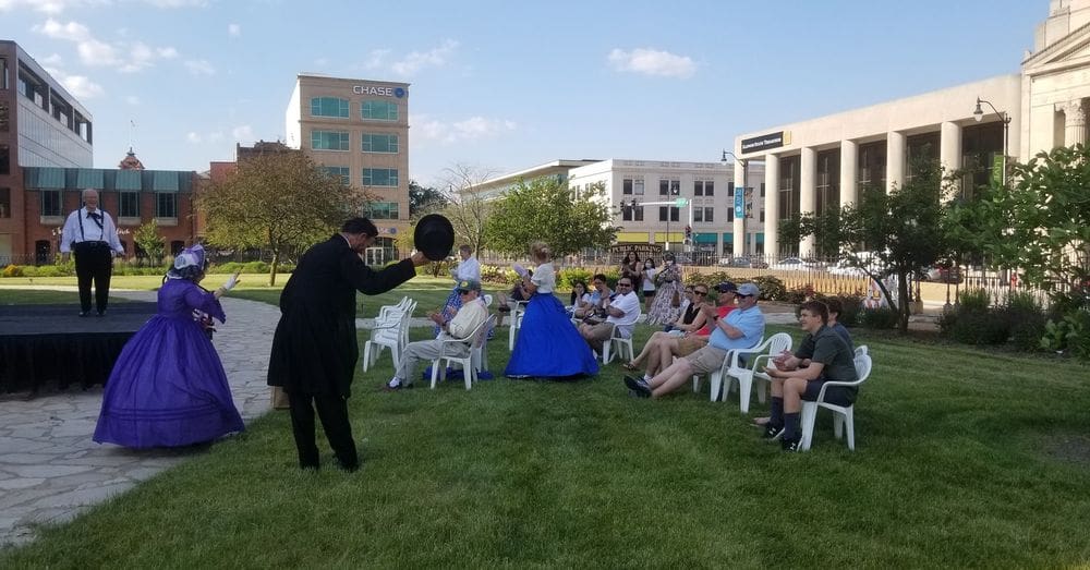 Several onlookers enjoy a show featuring actors playing Mary Todd Lincoln and Abraham Lincoln outisde on a sunny day in Springfield, Illinois, one of the best weekend getaways near Chicago for families