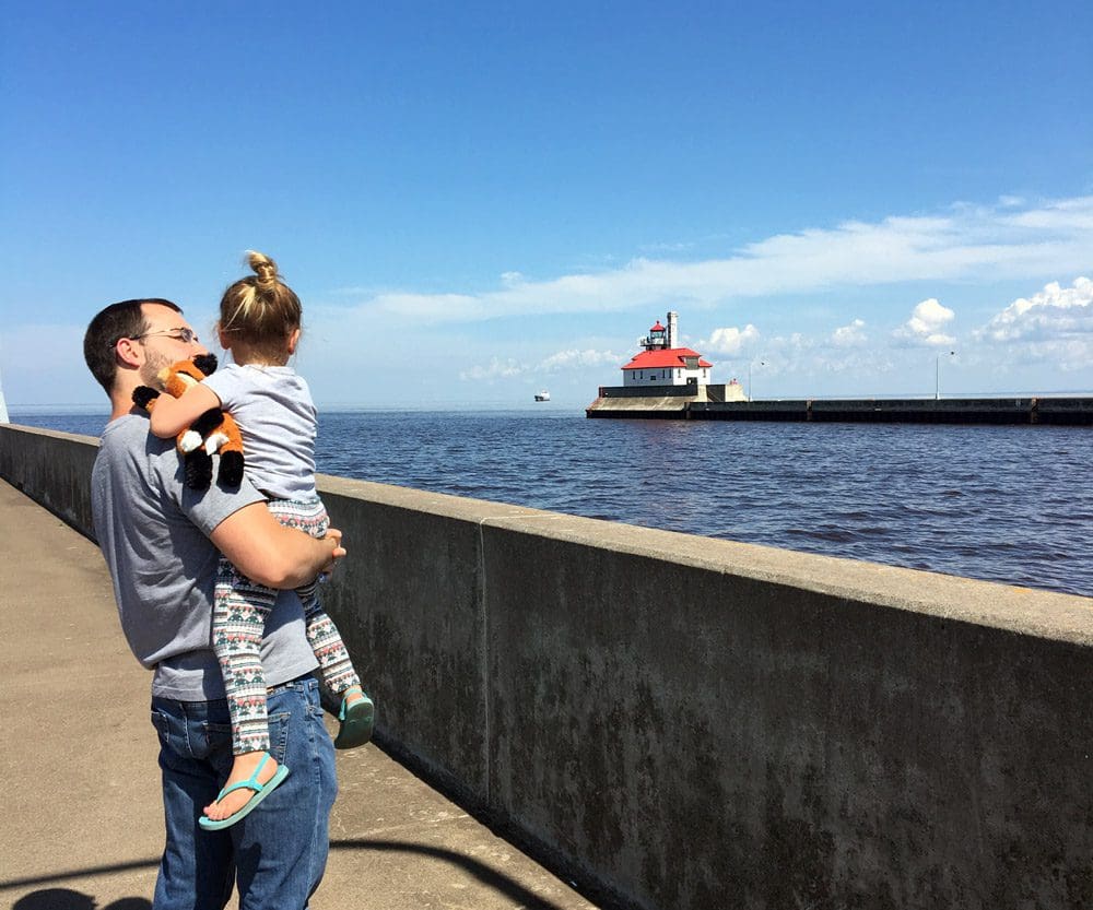 A dad holds his young daughter while walking along the pier viewing Lake Superior in Duluth, Minnesota.