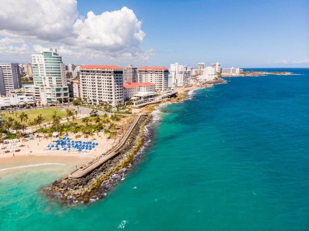 View of the crystal blue ocean and the golden sand shoreline at the Condado Vanderbilt Hotel, one of the best family resorts in Puerto Rico.