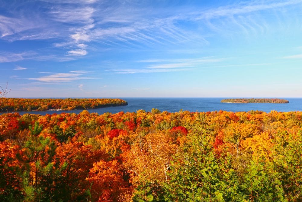 An aerial view of brilliant fall foliage in reds, oranges, and yellows at Peninsula State Park in Door County Wisconsin.