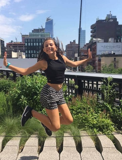 A girl jumps for joy while enjoying a sunny day on the High Line, one of the best New York City outdoor activities for kids.