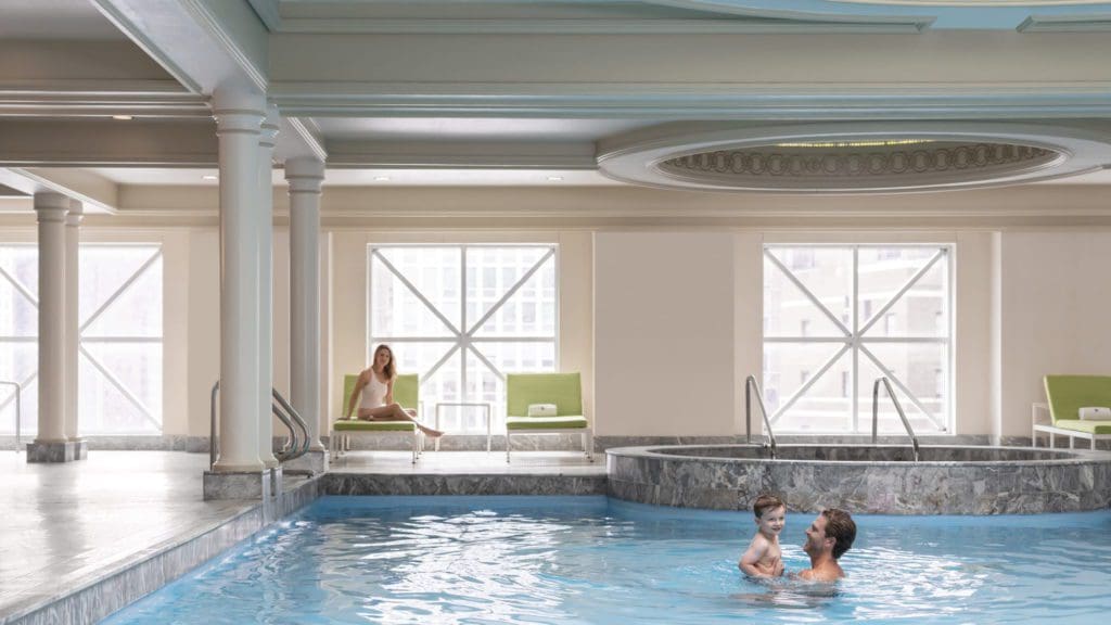 Photo of a father and his son playing in the indoor pool at the Four Seasons Chicago, one of the best family hotels in Chicago.