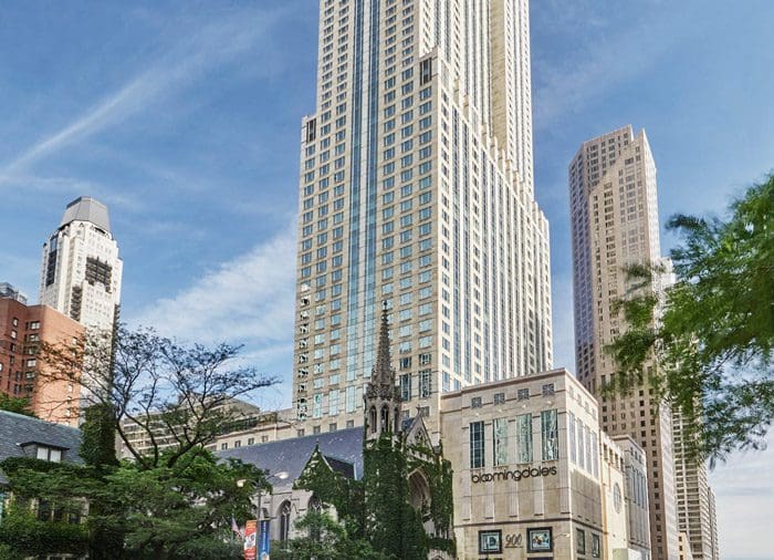 A view of the Four Seasons Hotel Chicago during the day, surrounded by other large buildings and tall trees.