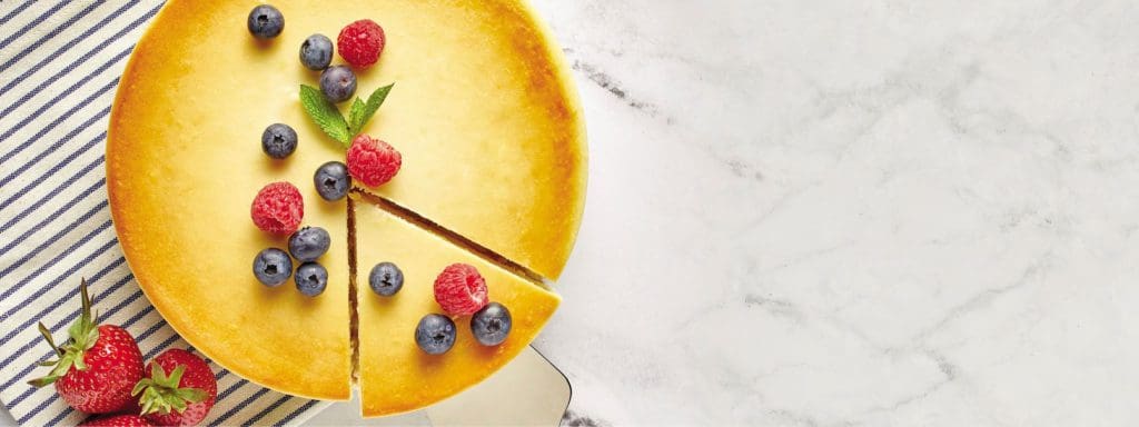 A gorgeous cheesecake, surrounded by fresh fruit, sits on a table at Junior’s Restaurant and Bakery, one of the most unique New York City restaurants with Kids.
