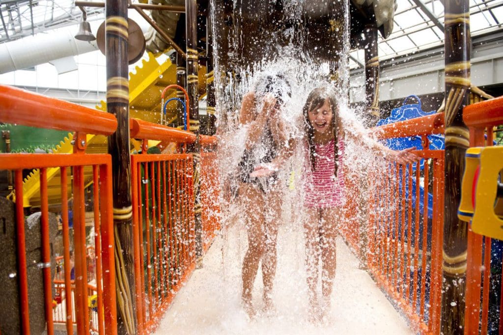 Two girls run across a splash bridge at Kalahari Resort Poconos Mountains, one of the best resorts in Pennsylvania for families.