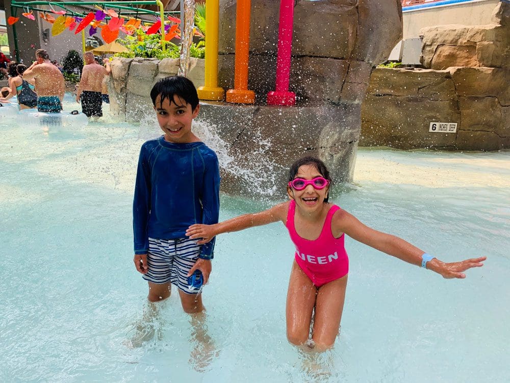 Two kids in swim suits enjoy a splash at the indoor waterpark at Kartrite.