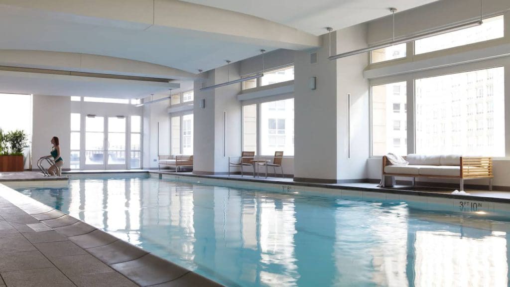 A woman in a green bathing suit emerging from the indoor pool at the Park Hyatt Chicago, one of the best family hotels in Chicago.