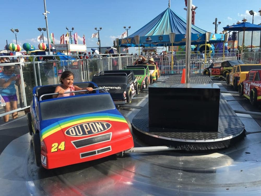 A young girl holds tightly to a ride bar while enjoying a race car ride at Coney Park.