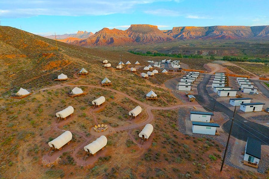 Several covered wagons, safari tents, and cabins dot the desert at Zion Wildflower Resort, this is one option for where to stay near Zion National Park with kids!