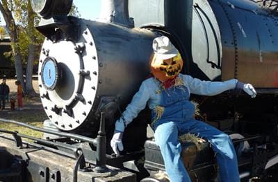 A pumpkin scarecrow leans against a train engine at the Harvest Haunt at the Colorado Railroad Museum.