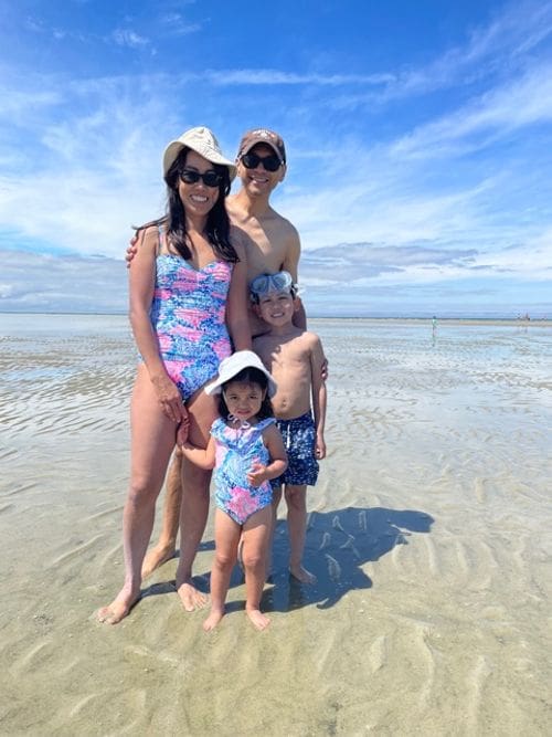 A family of four in matching swimming suits stands together in the water off-shore from Cape Cod.