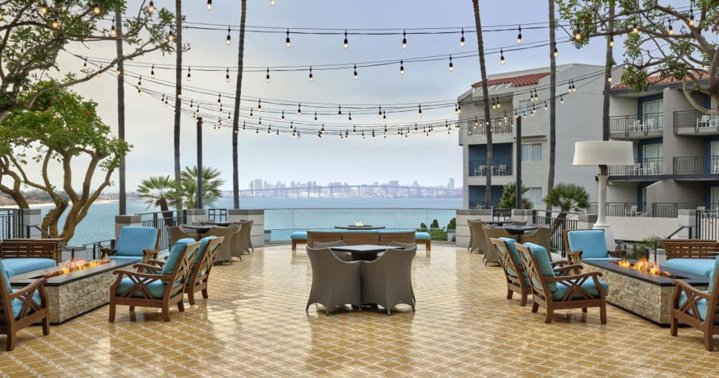 The deck with fire pit feature and several seating areas with overhead twinkle lights at the Loews Coronado Bay Resort.