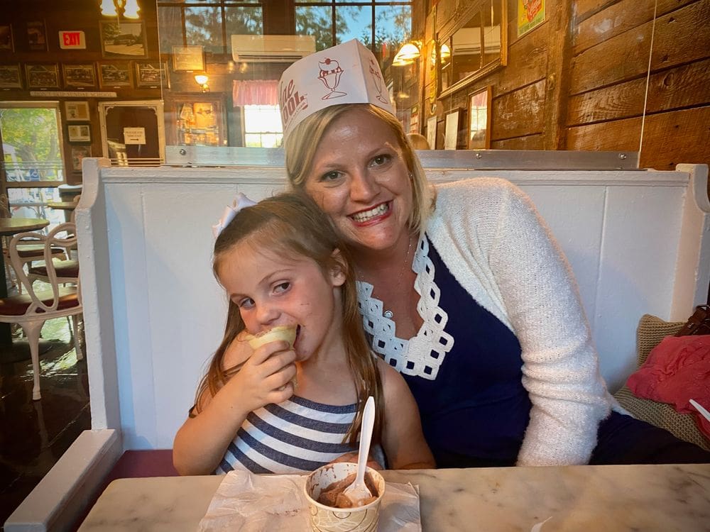 A mom and her daughter sit in a cozy booth at Sundae School munching on ice cream.