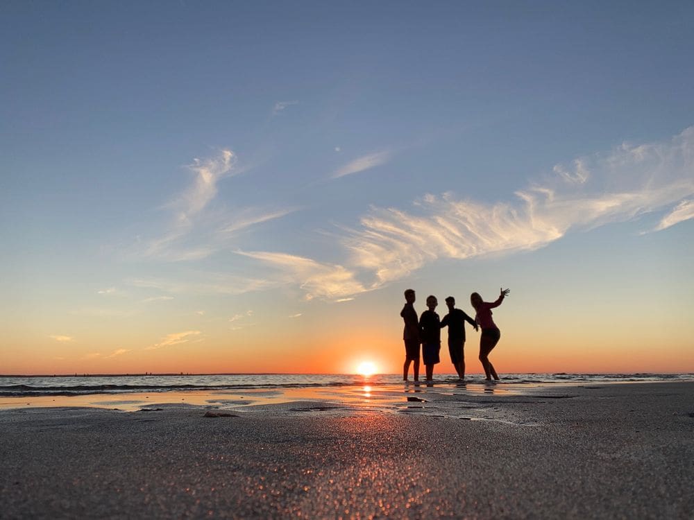 A family of four stands together at sunset on the Mayflower Beach in Cape Cod, one of the best Labor Day Weekend getaways near NYC with kids.