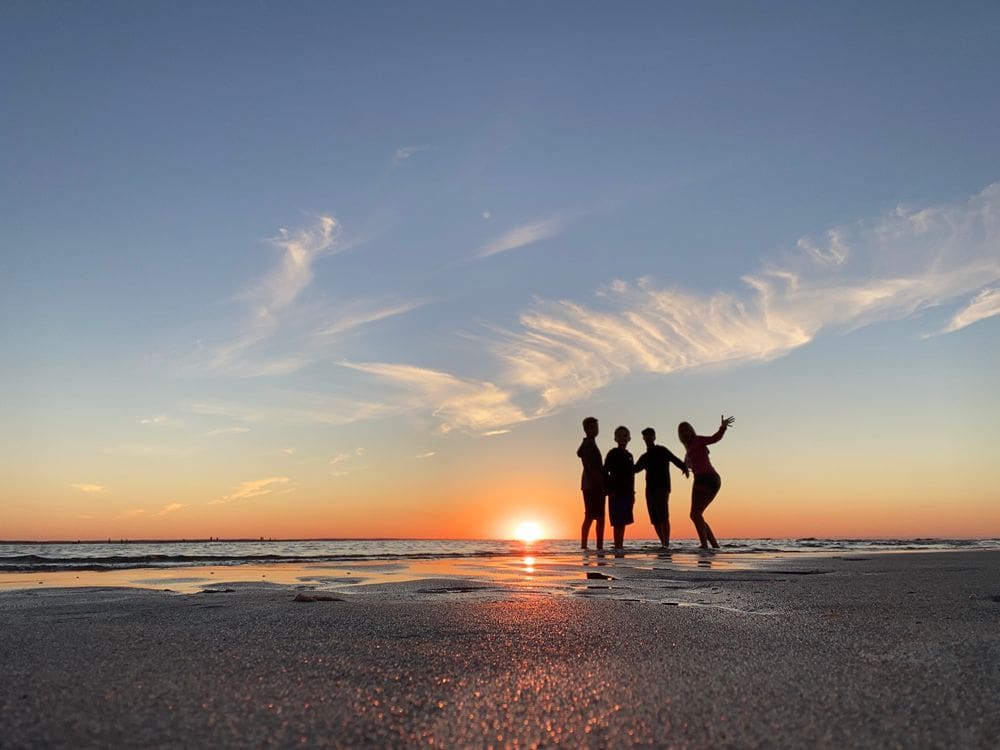 A family of four stands together at sunset on the Mayflower Beach in Cape Cod.