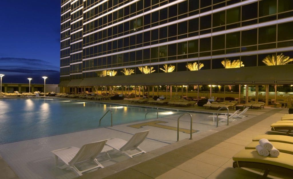 The outdoor pool at the Trump International Hotel Las Vegas, with surrounding pool deck and poolside loungers, at night.