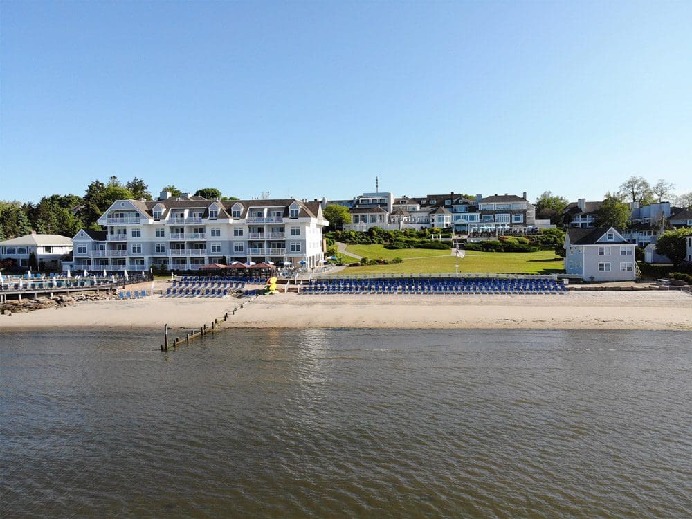 A view of the Water’s Edge Resort and Spa from the water, featuring a long shoreline on a sunny day.