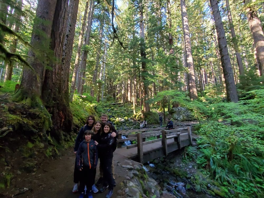 A family of five stands together while hiking along Sol Duc Falls in Washington.