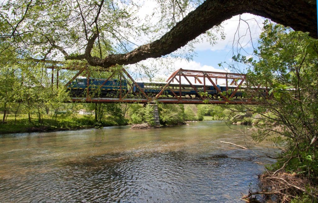 A train from the Blue Ridge Scenic Railway goes through a scenic over-water bridge, one of the best fall things to do in north Georgia for families!