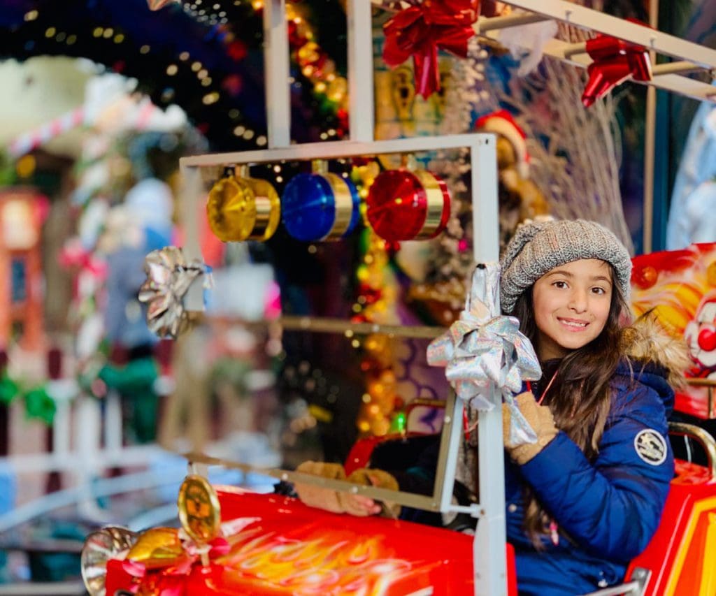 One kids ride an amusement car at a Christmas market in Colmar, France, one of the best places for Christmas for families in the world.