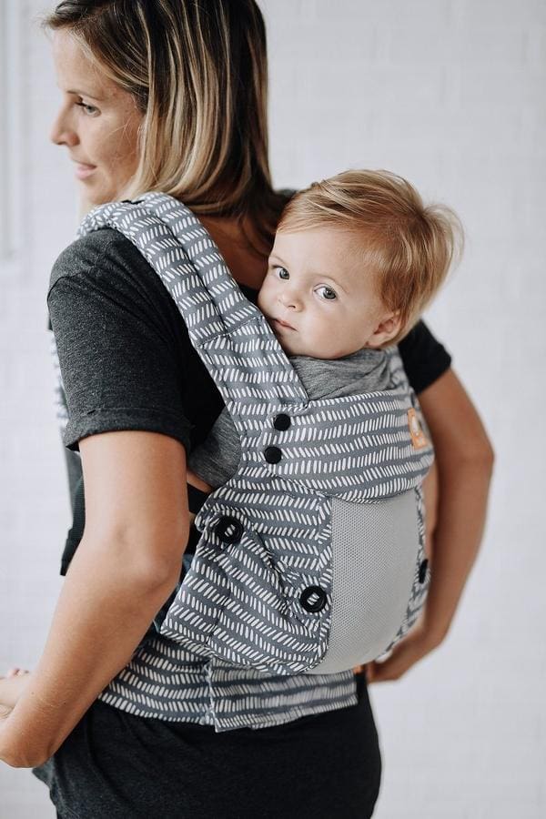 A close up of a baby snuggled in a Tula Coast Explore Mesh Baby Carrier, riding on his mother's back, one of the best Best baby carriers for travel.