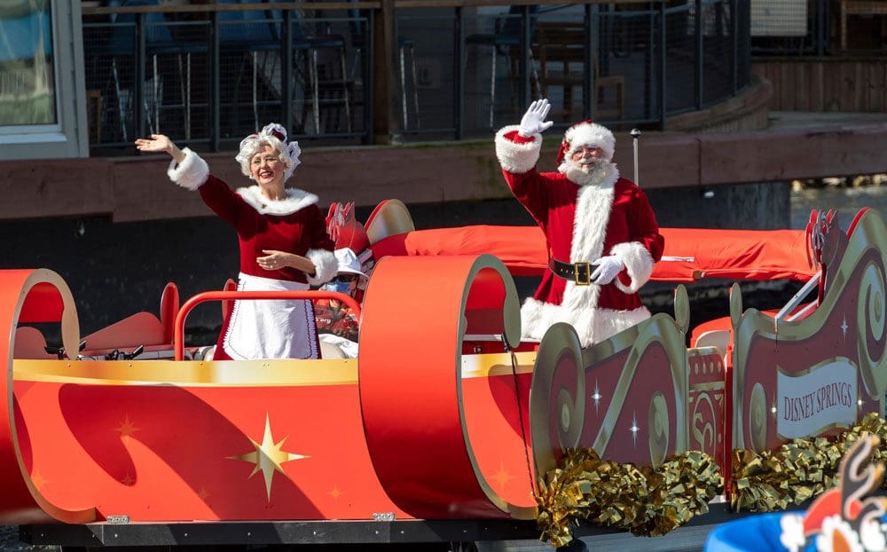 Santa and Mrs. Clause wave from a red sleigh at Disney Springs, a great event for celebrating the holidays in Disney as a family.