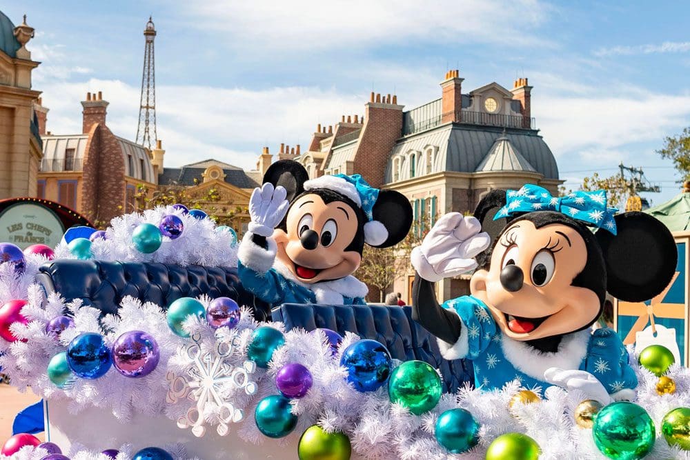 Mickey and Minnie dressed in blue holiday outfits wave from a blue sleigh during the winter holidays at Epcot, one of the best events for the holidays in Disney as a family.